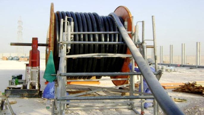 Power cable being drawn from drums during a distribution install