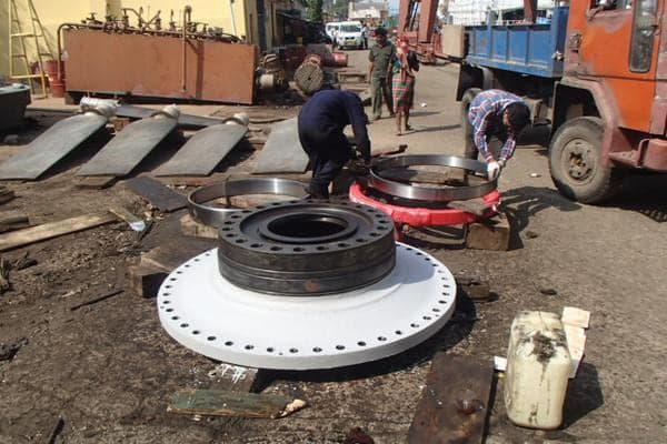 Crew handling a large machined flange during a tug overhaul