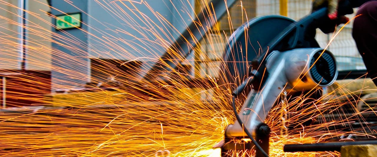 Angle grinder throwing sparks across a steel component in the Leo Enterprises workshop