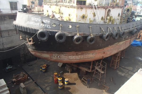 A tug sitting on blocks in dry dock during hull maintenance